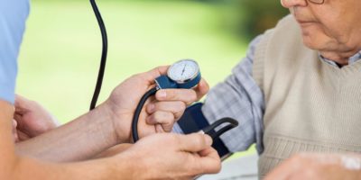 Läkare mäter blodtryck på äldre man
