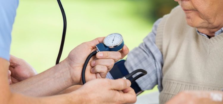 Läkare mäter blodtryck på äldre man